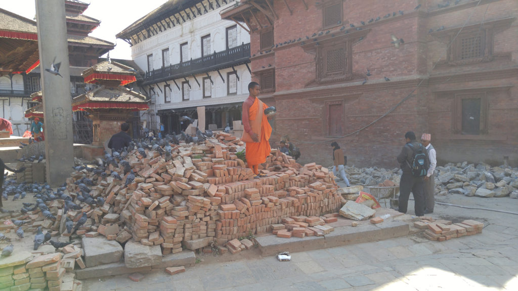A monk stands on the rubble of a destroyed temple
